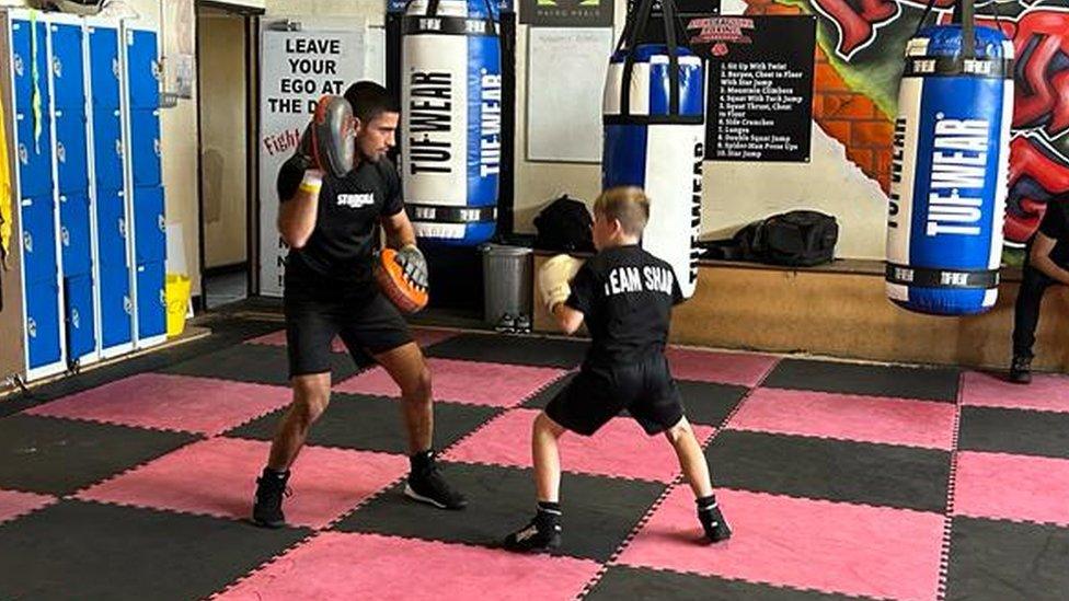 A man teaching a young boy boxing skills