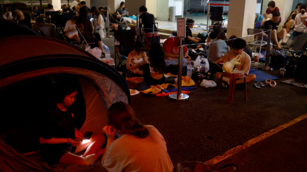 Sera, 14, and Eliza, 14, prepare to sleep in their tent as they queue overnight for Taylor Swift concert tickets outside a post office in Singapore, Singapore July 6, 2023