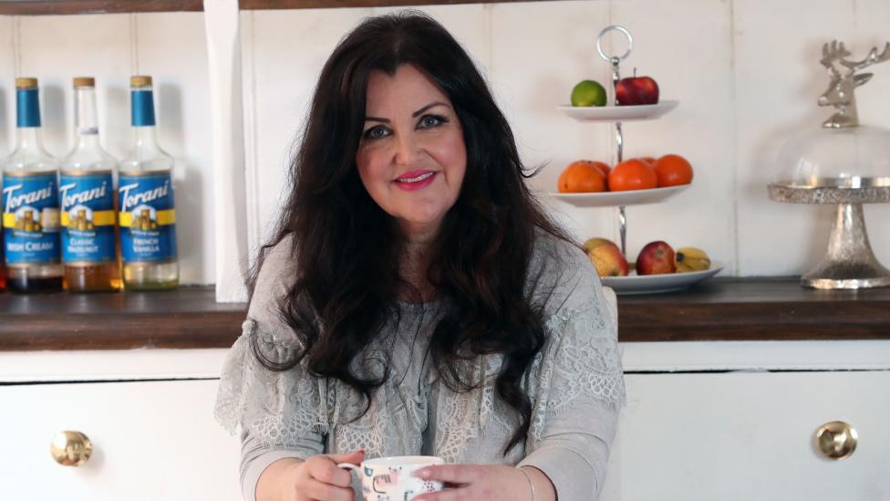 Kate sitting at a kitchen table with a tea cup