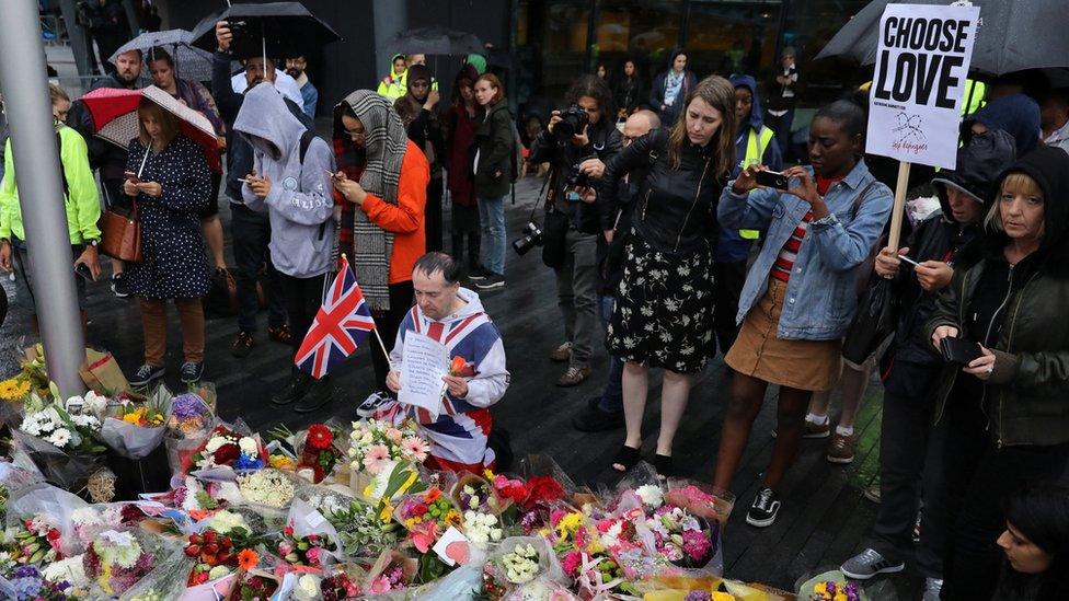 A man kneels before floral tributes after a vigil in central London