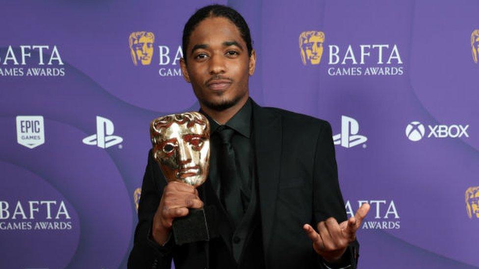 Nadji Jeter holding a golden mask Bafta award for playing Miles Morales in Spider-Man 2