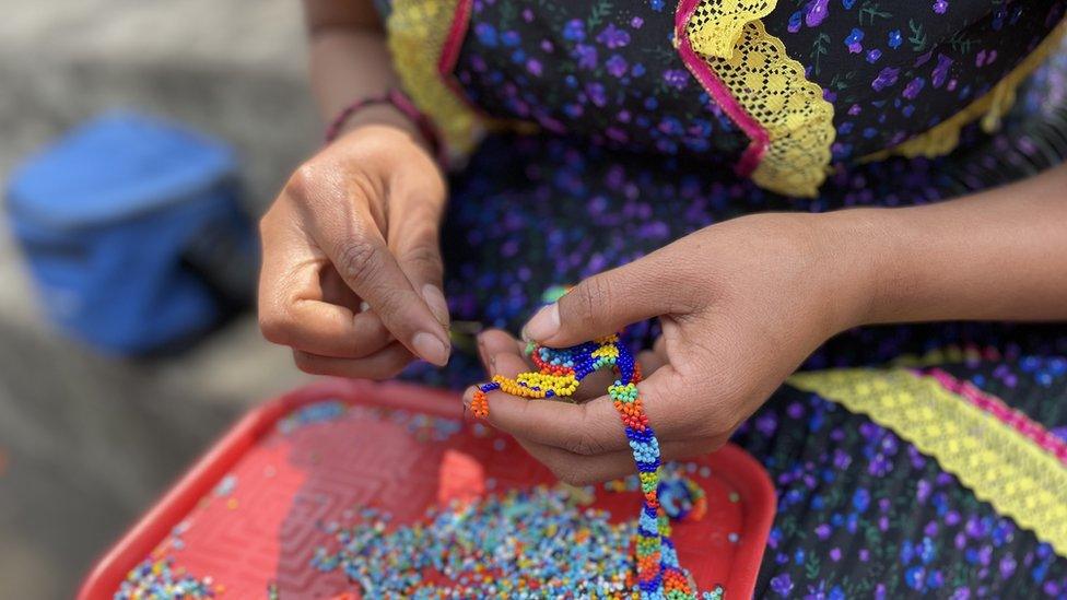 An Emberá woman works on a bead necklace