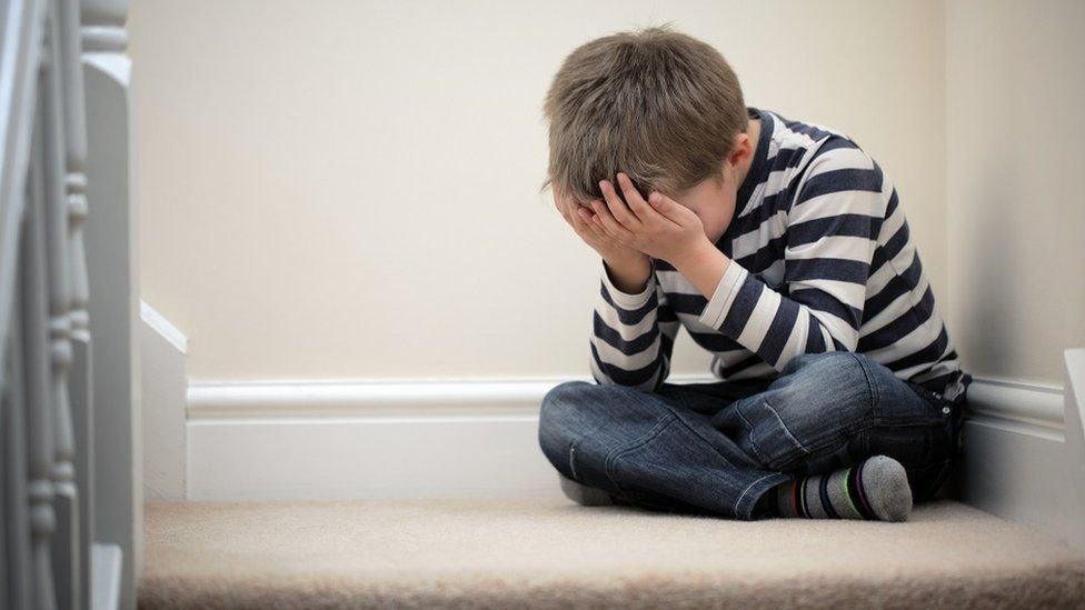 Child sitting on steps with face in hands