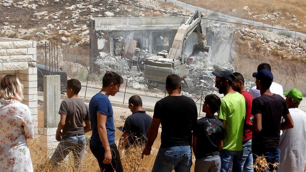 Palestinians watch Israeli army excavator demolishing a building in Wadi Hummus, in the occupied West Bank (22 July 2019)