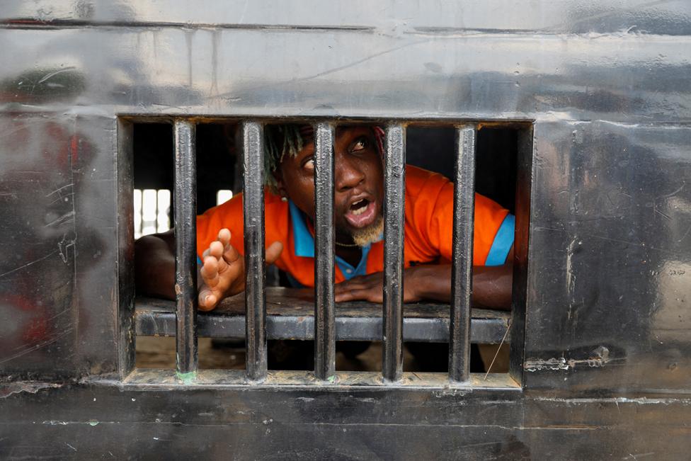 A demonstrator reacts as he is detained in a police van in Lagos, Nigeria, 20 October 2022.