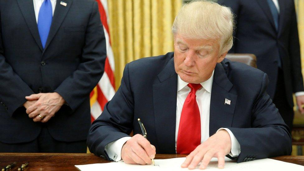 President Donald Trump signs first executive orders in Oval Office in Washington, January 20, 2017