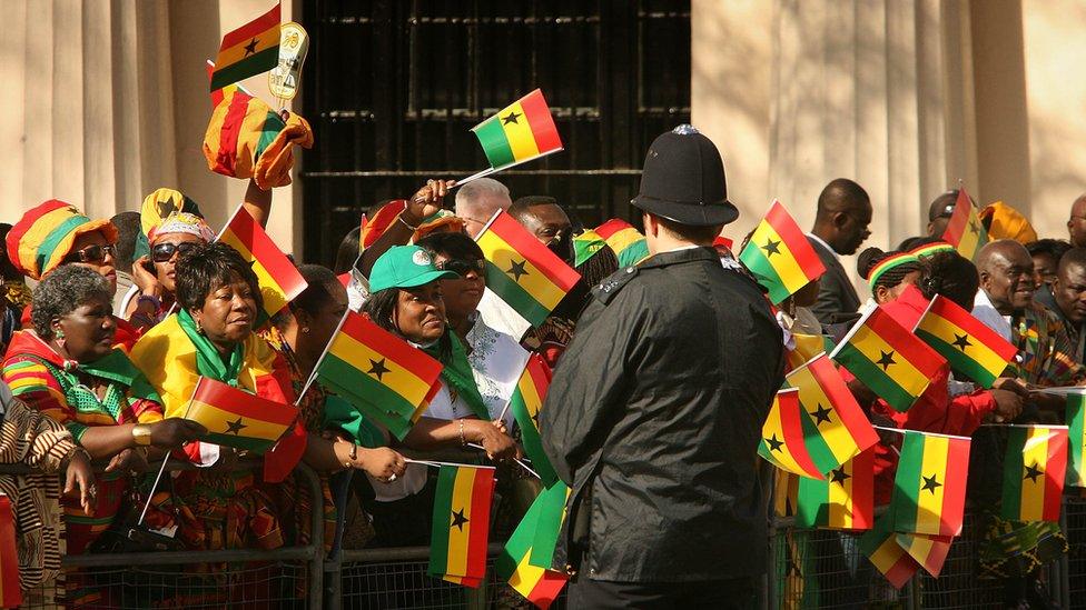 Ghanaians in London wave flags as they wait on the Mall ahead of a visit by Ghana's president to the UK - March 2007