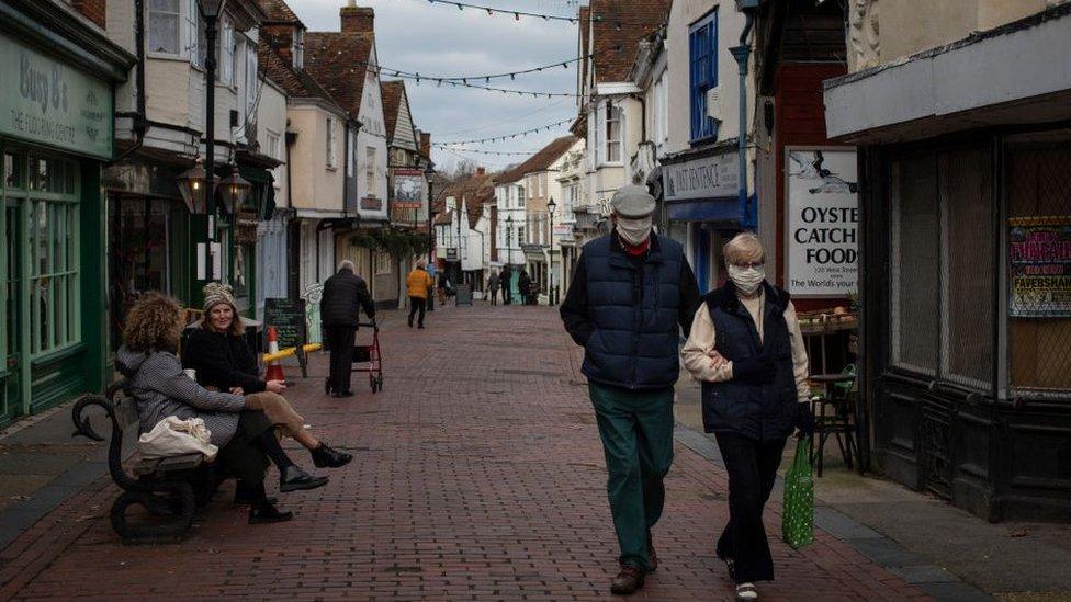 Members of the public wearing face masks walk down a high street in Faversham