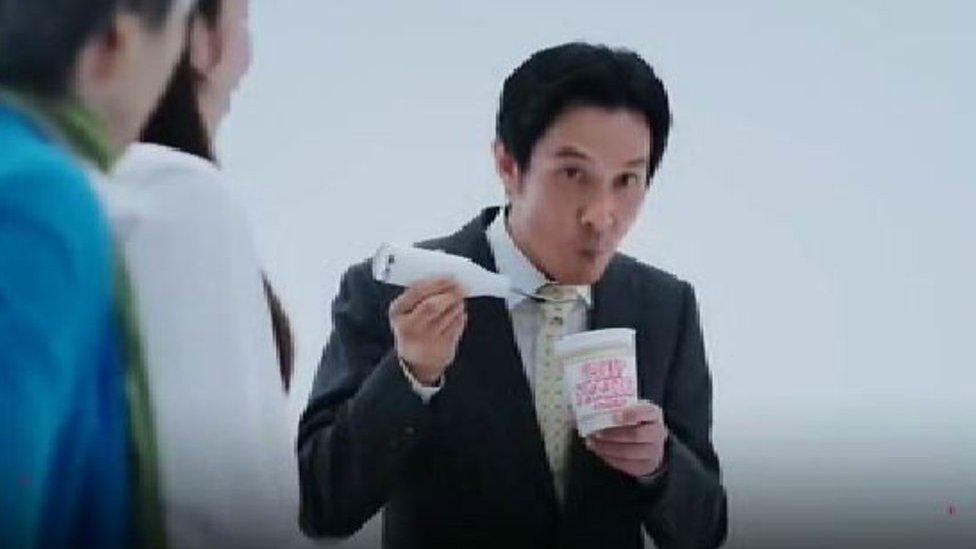 man looking up from his ramen bowl