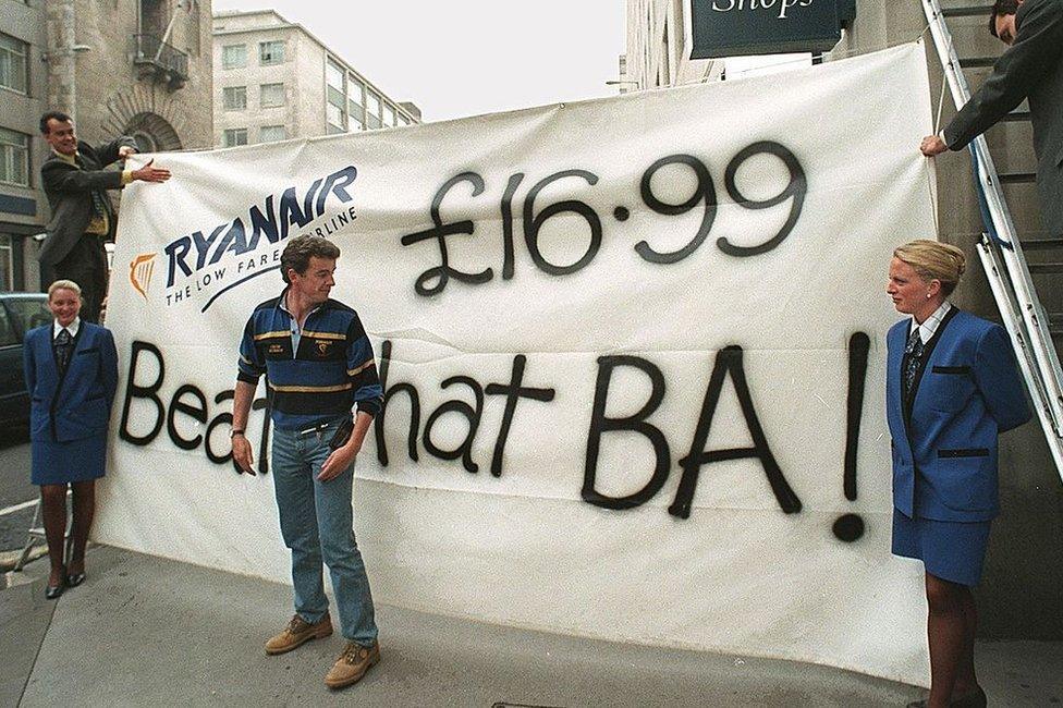 Ryanair's chief executive Michael O'Leary looks at a banner the company erected outside of rival British Airways travel shop 03 September. 1998