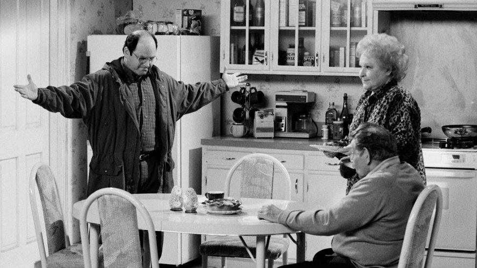 Image shows Jason Alexander, Estelle Harris and Jerry Stiller on set of Seinfeld