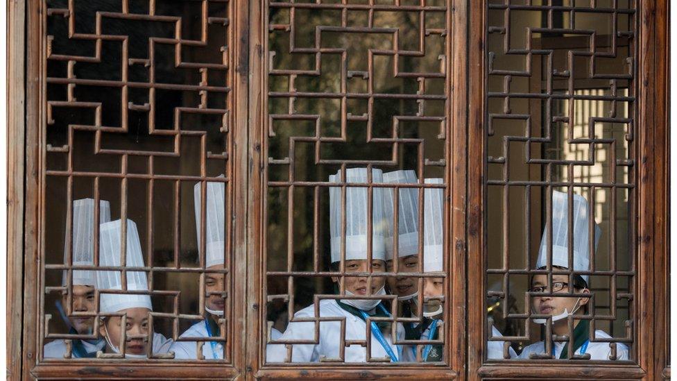 Chefs standing behind a wooden lattice window in Wuzhen