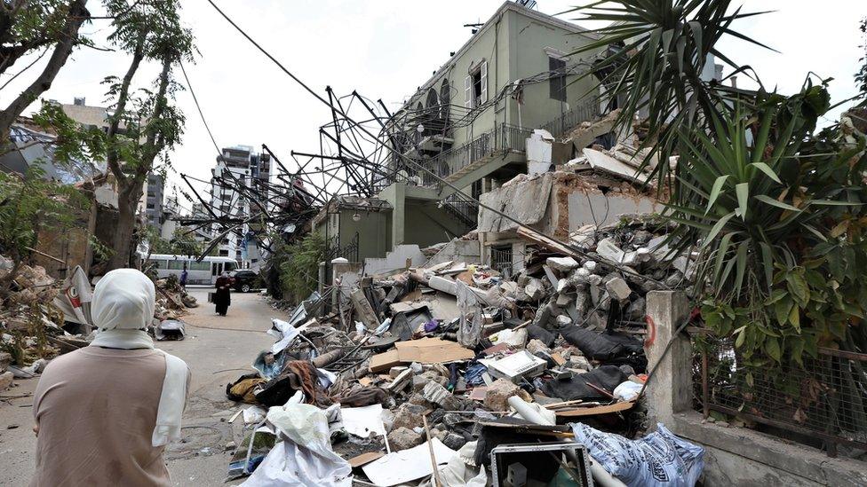 A woman looks at damaged buildings in the Karantina area of Beirut (9 August 2020)