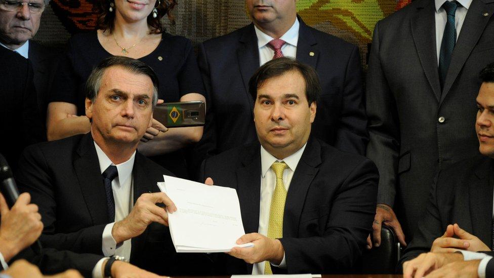 Brazil's President Jair Bolsonaro and Lower House President, Rodrigo Maia pose with the proposal of the pension system reform bill at the National Congress in Brasilia, Brazil February 20, 2019