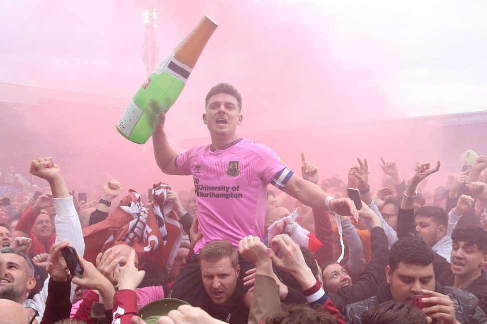 Northampton Town fans and Sam Hoskins celebrate promotion after the Sky Bet League Two match at Prenton Park