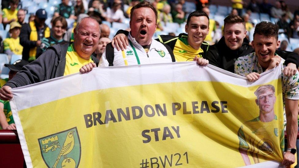 Five Norwich City fans in Villa Park stadium hold a "Brandon Please Stay" banner as the team played Aston Villa on 30 April 2022