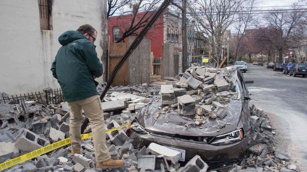 An insurance company employee checks the damage to a car after a partially burnt building collapsed due to strong winds in Northeast Washington, DC.