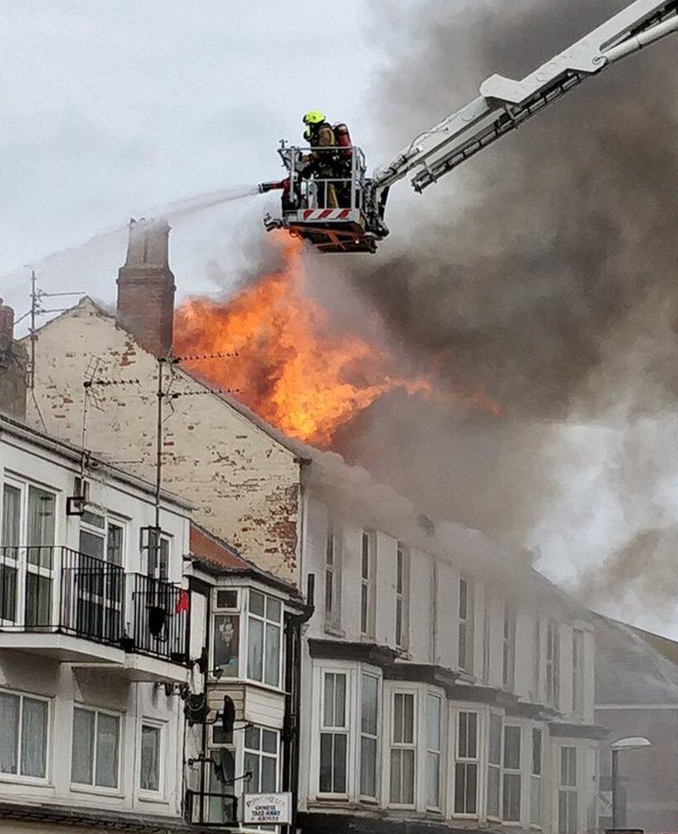 Firefighters putting out a fire in the roof of a hotel building