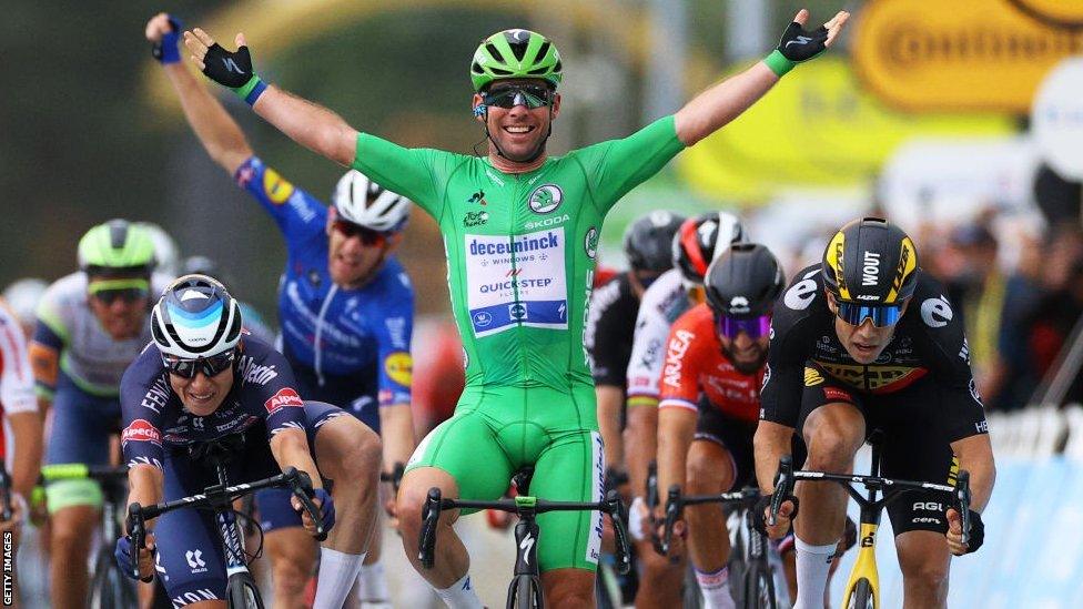 Mark Cavendish sits up in the saddle and has a huge smile, lifting his arms aloft as he crosses the line to win a stage at the 2021 Tour de France