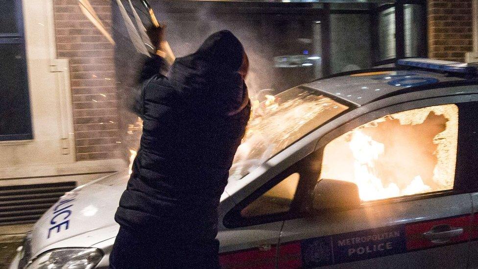 A protester attacks a parked police car