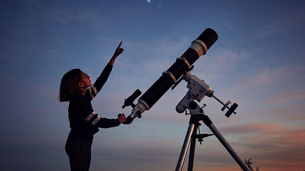 Child with telescope pointing at the sky