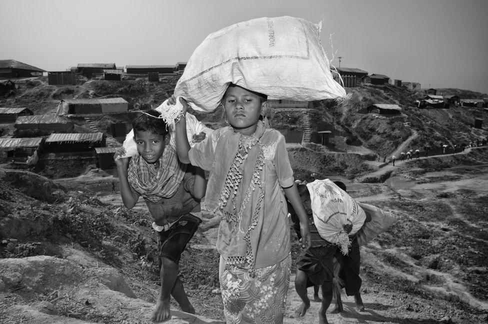 A child carries a bag on her head