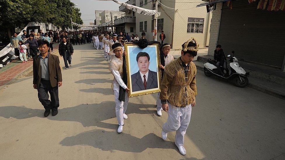 The son of Xue Jinbo (portrait), a 42-year-old village leader who died in police custody, Xue Jindi (R) and locals attend the funeral ceremony in Wukan, a fishing village in the southern province of Guangdong on 16 December 2011