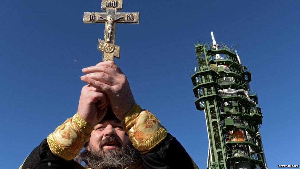 A Russian Orthodox priest conducts a ceremony near a Soyuz spacecraft before launch