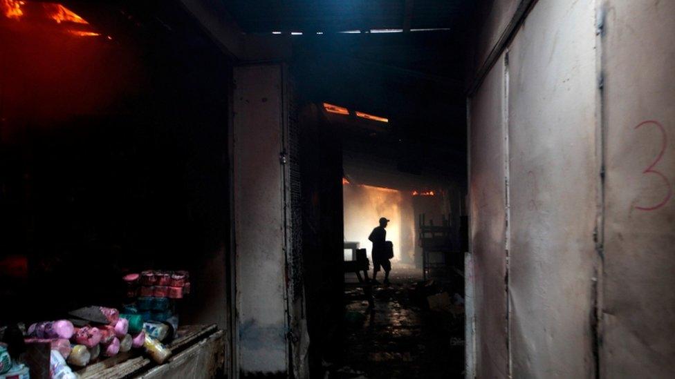 A man carries a bucket of water as he helps to extinguish a fire at the oriental market,