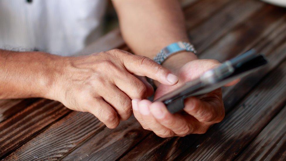 File photo of an elderly Japanese man's hands typing on a smartphone