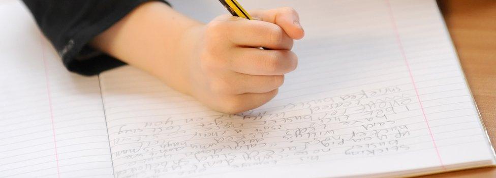 Primary school child writing in an exercise book