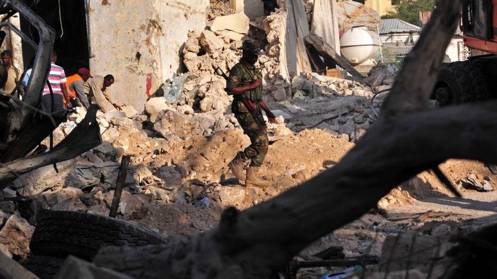 A Somali security force officer walks among ruins at scene of Saturday blast in Mogadishu