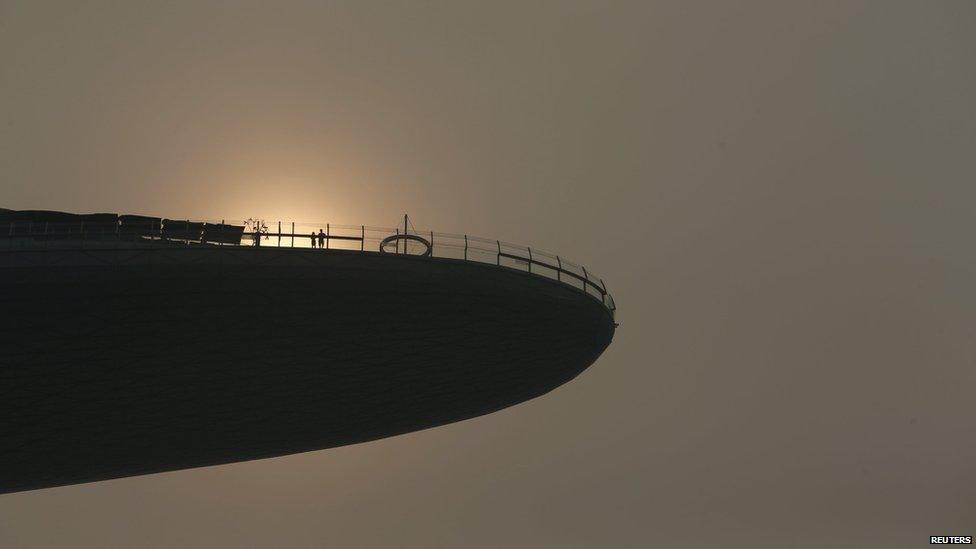 Tourists watch the sunset at Singapore's Marina Bay Sands which is covered by haze