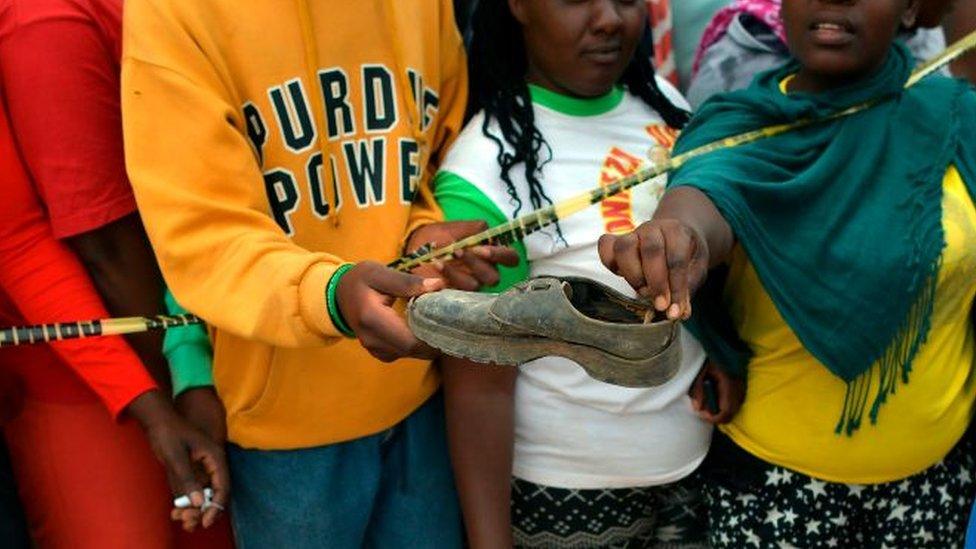 A crowd of onlookers pick up an abandoned shoe at the scene of the Precious Talent Top School collapse in Nairobi on 23 September.