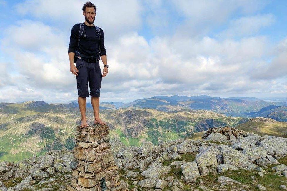 Matt Scott stands on top of a trig point in barefoot