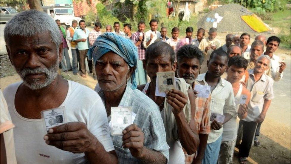 Indian voters show their voter ID cards as they stand in a queue to vote at a polling station in Samastipur, Bihar, India, 12 October 2015