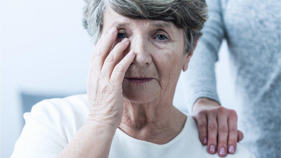 Older woman touching her face