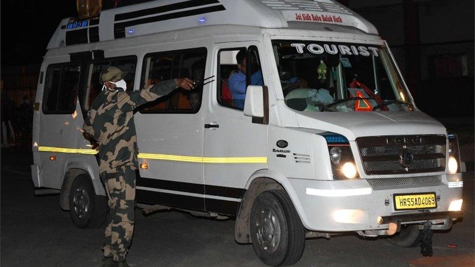 A Border Security Force (BSF) personnel check a mini bus with two officials of the Pakistan High Commission with their families on board as they return to Pakistan at the India Pakistan Wagah Border post on June 1, 2020.