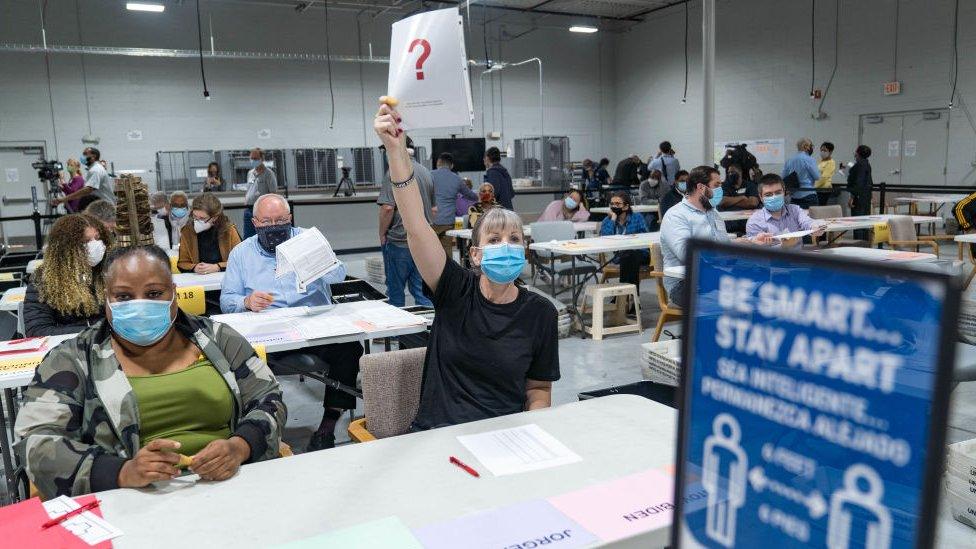 A Gwinnett county worker raises a piece of paper saying that they have a question as they begin their recount of the ballots on 13 November 2020