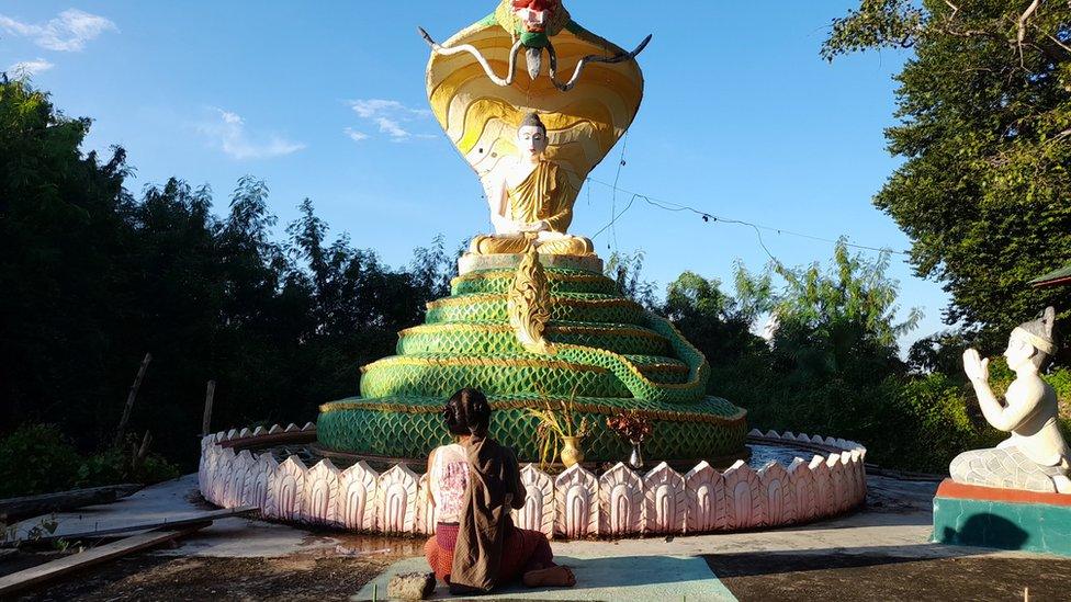 Mum Yin Yin Myint kneeling in front of a pagoda