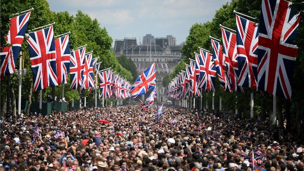 Thousands of people on the Mall in central London, with hundreds of Union flags lining the road