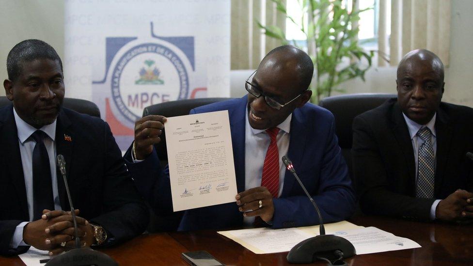 Haiti's Minister of Planning and External Cooperation Aviol Fleurant (centre) shows a statement about the Oxfam case at a news conference in Port-au-Prince on 13 June 2018