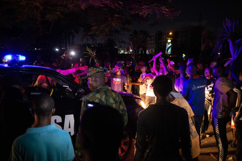 A patrol car drives amongst protesters