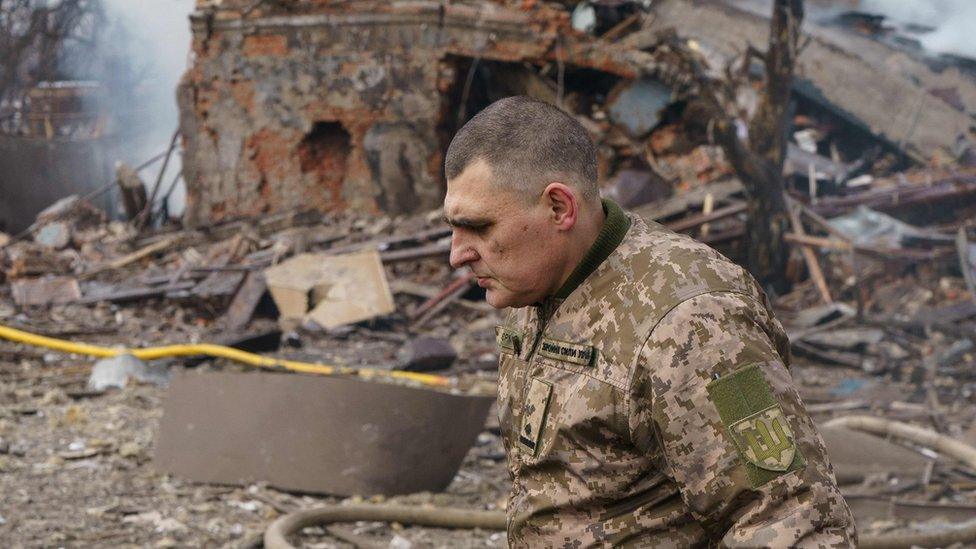 Ukraine army public affairs officer Valentin Yermolenko walks in front of a destroyed shoe factory following an airstrike in Dnipro on 11 March 2022.