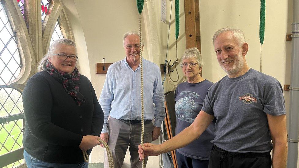 Bell ringers stand around a rope