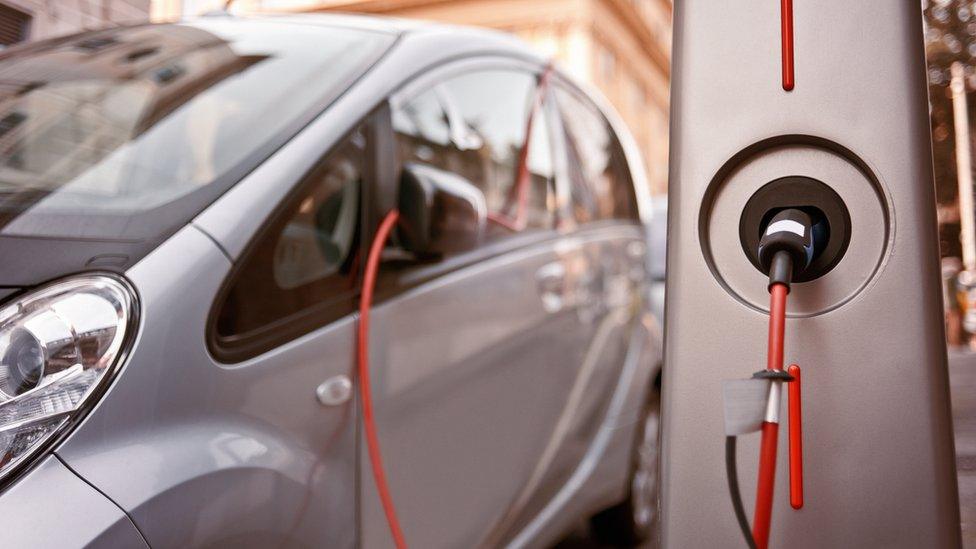 An electric car charging on the street.