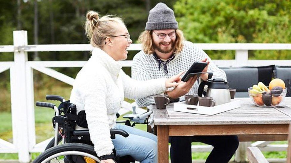 woman in wheel chair laughing at a desk with a man