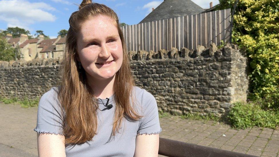 Summer Auty smiling with a brick wall in background