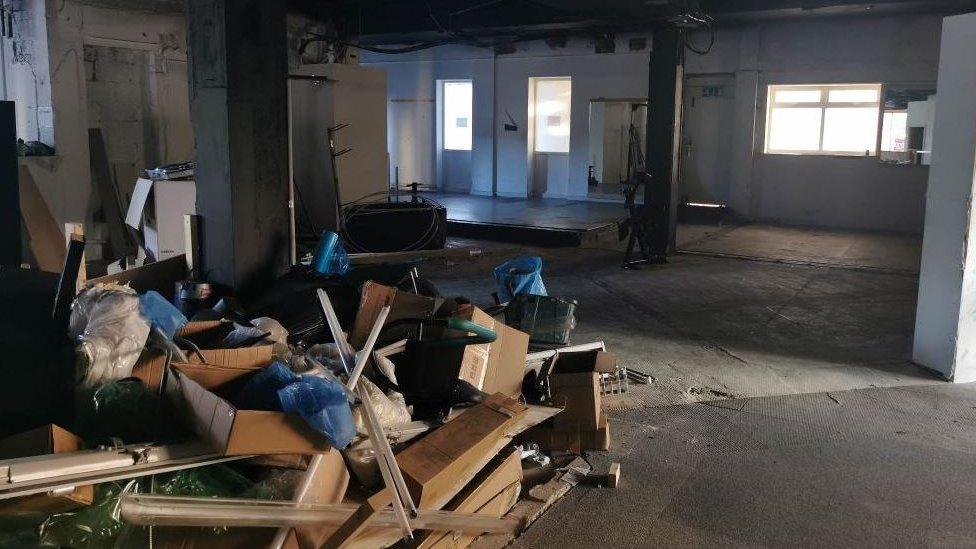 Ground floor of the Amulet theatre covered in debris, rubbish and broken wooden panels