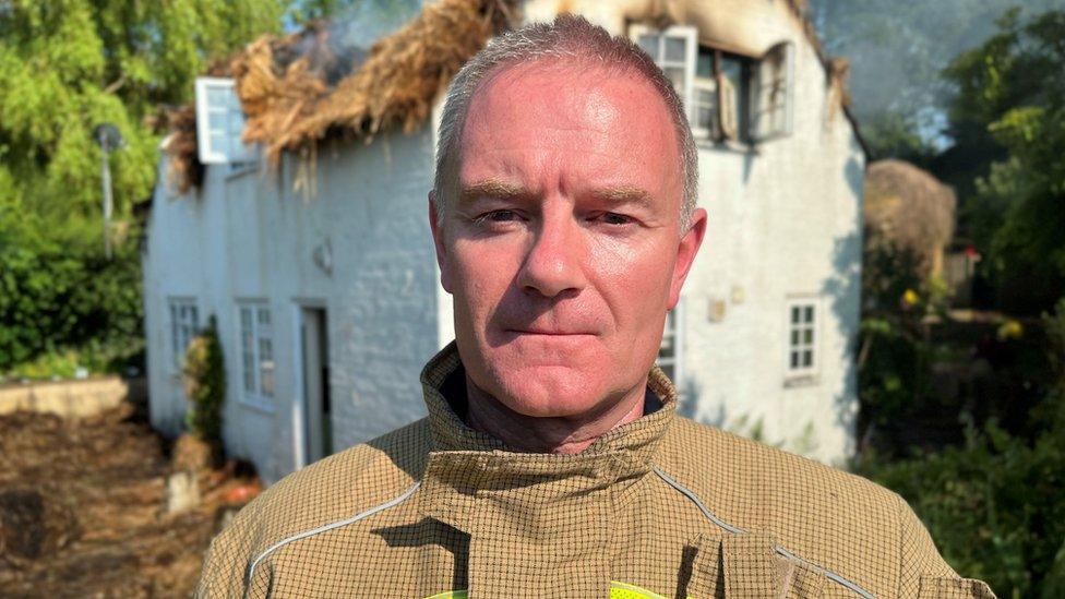 Firefighter Wayne Jones standing in front of the burnt building